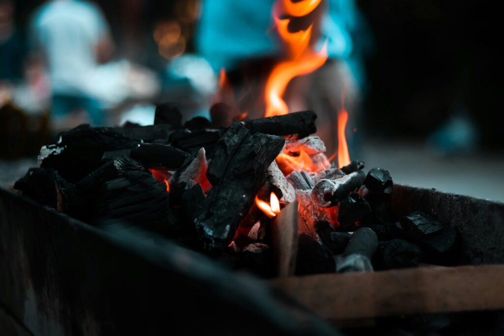 Intense close-up of charcoal igniting with vibrant flames in an outdoor setting.